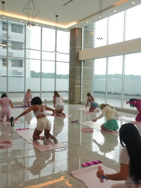 Clase en un salón de cristal con mats rosados y aros de Pilates